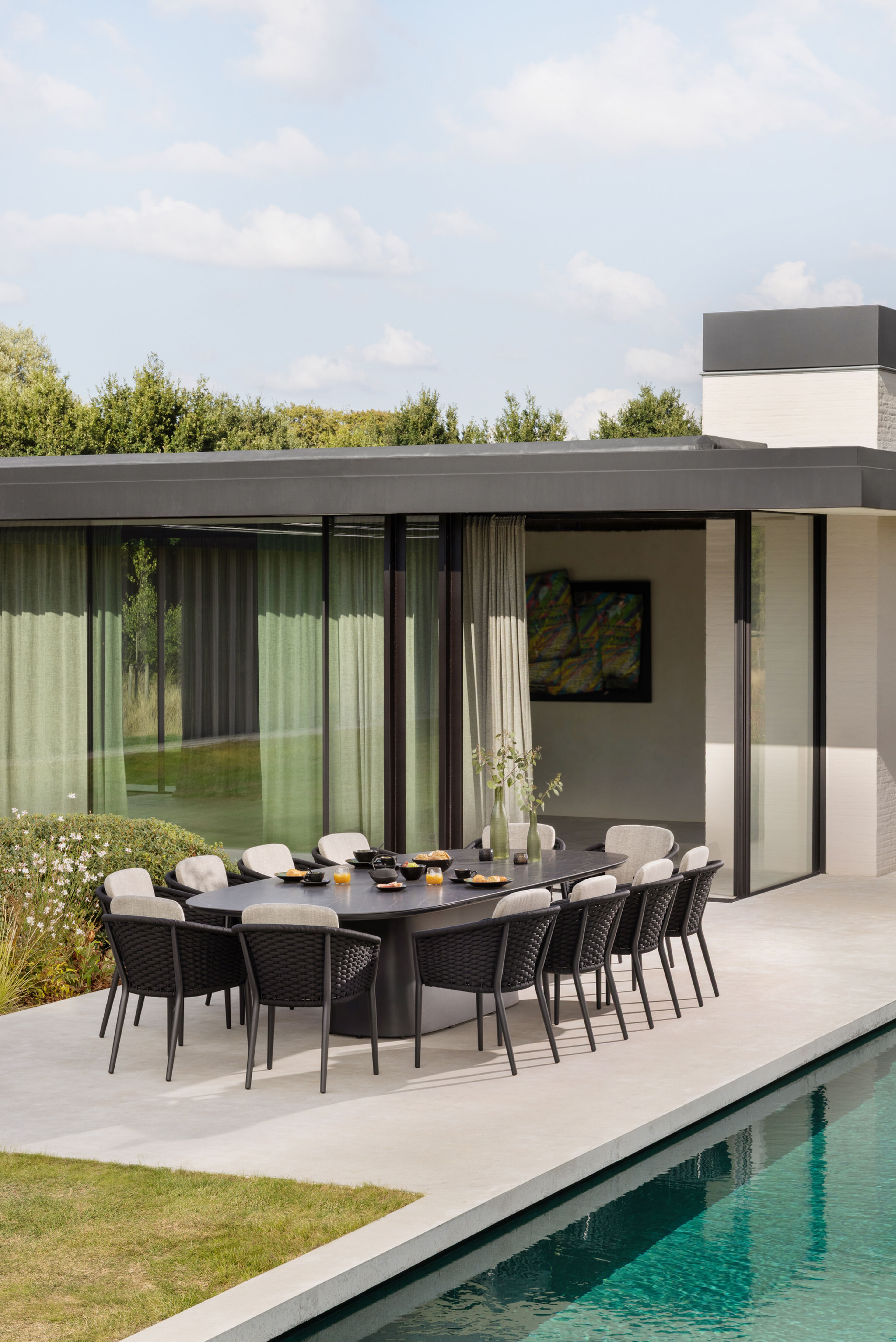 Orso stapelbare tuinstoel in zwart aluminium en zwart horizontaal geweven ronde rope met stoelkussen in All Weather Sunbrella® Luxe Natte Linen Chalk