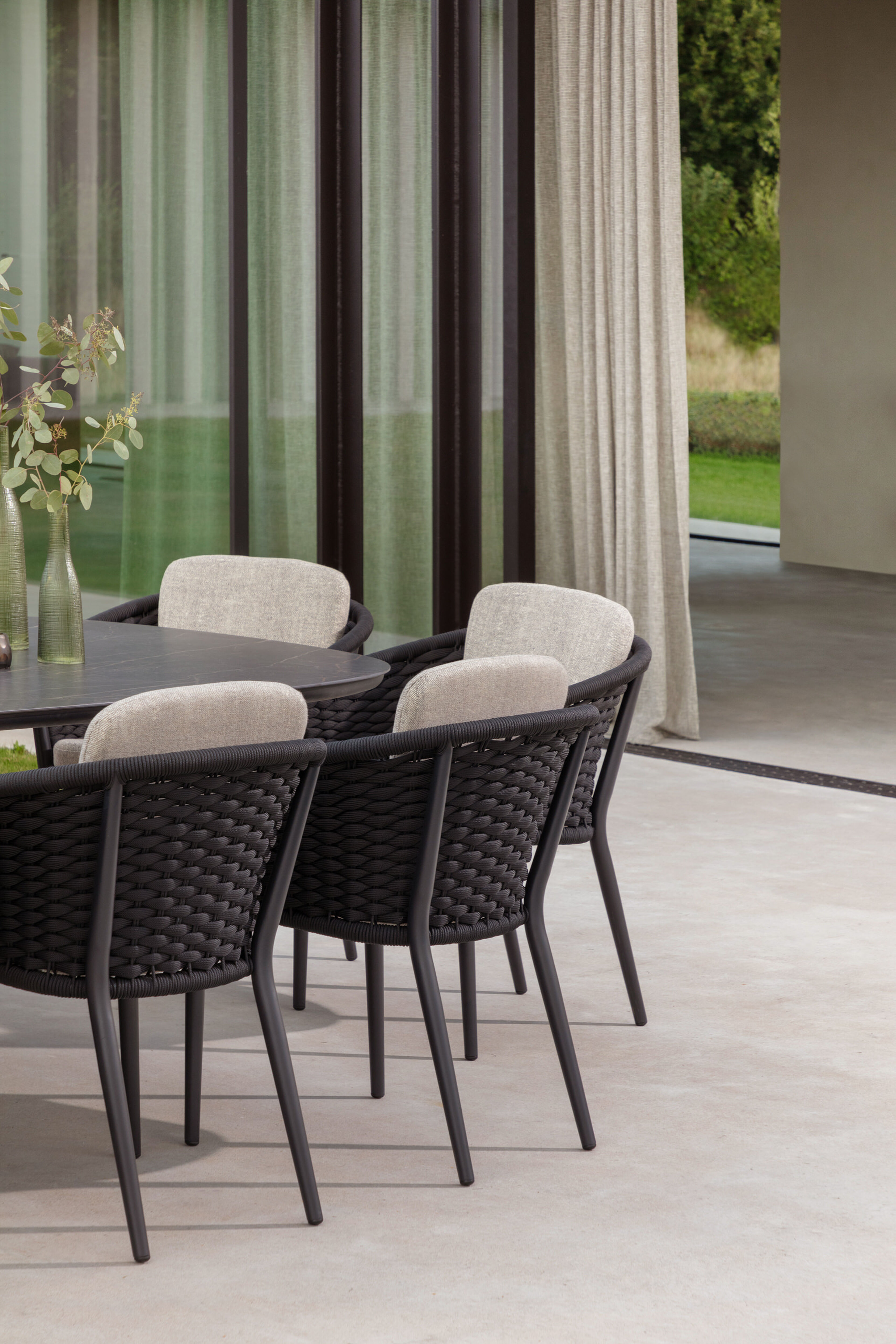 Orso stapelbare tuinstoel in zwart aluminium en zwart horizontaal geweven ronde rope met stoelkussen in All Weather Sunbrella® Luxe Natte Linen Chalk