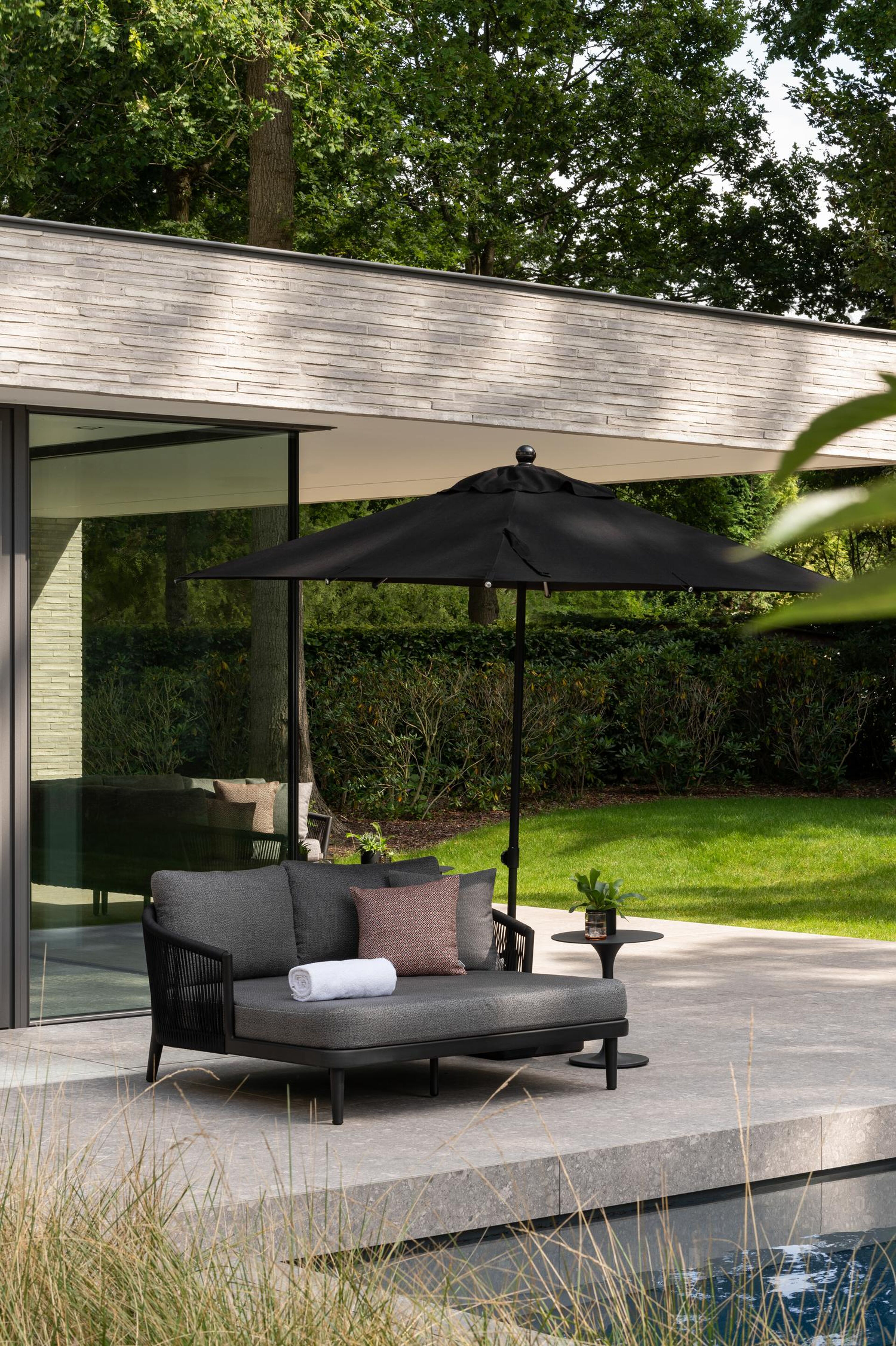 Chaise longue Orso en aluminium noir et corde ronde tissée verticalement noir avec coussin en All Weather Sunbrella® luxe savane tornado avec noir aluminium table d'appoint